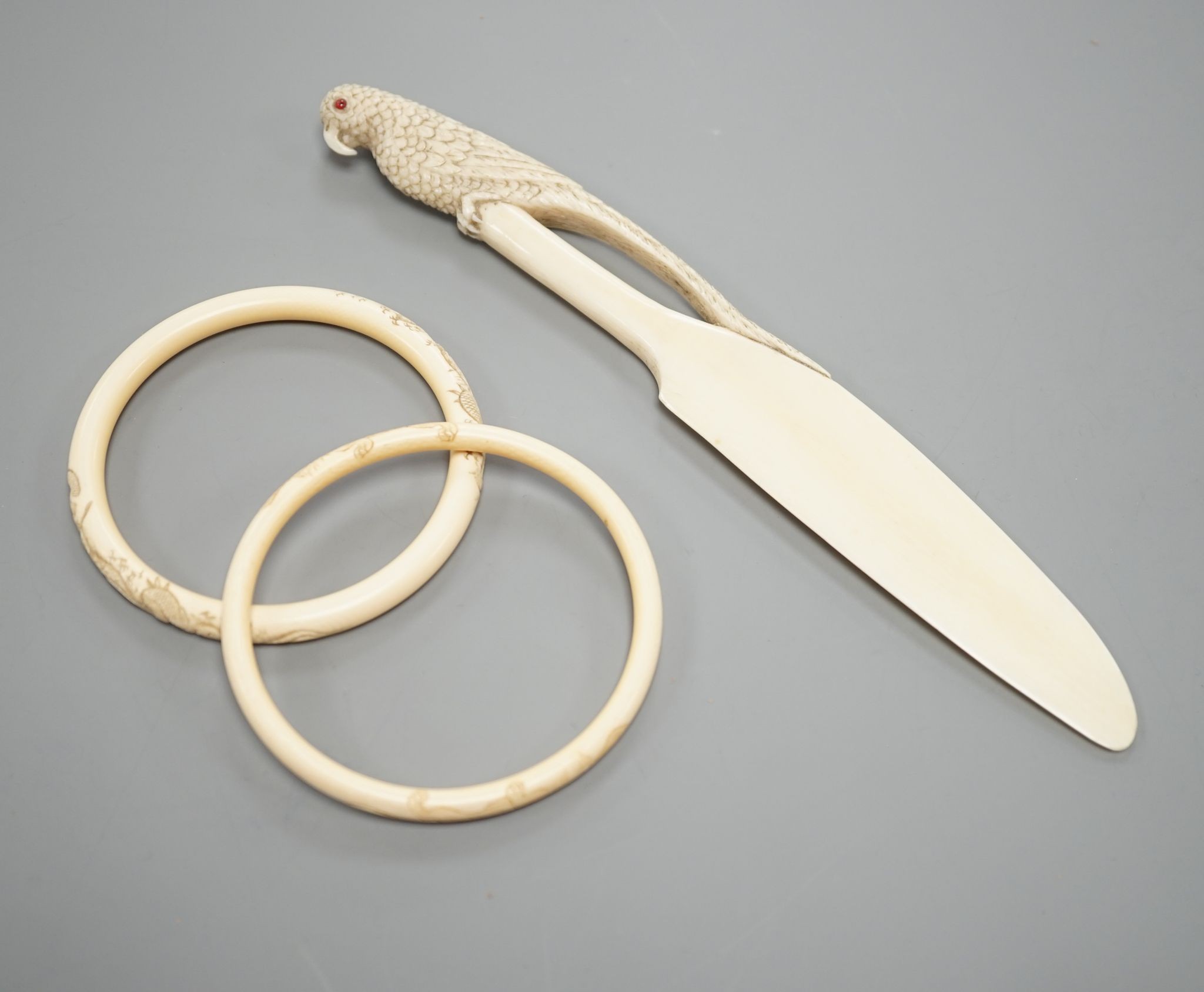A late 19th century carved ivory ‘parrot’ paper knife and two Japanese carved Ivory bangles, paper knife 22 cms long.